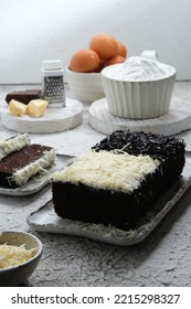 Chocolate Steamed Cake With Gratd Cheese And Messes As Topping. Egg, Cheese, Flour, Grater As Element With Rustic Background. Brownies Kukus  