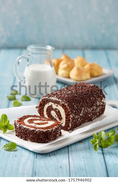 Chocolate Swiss Roll Cake coated with Chocolate Chips\
on blue wooden table\
top