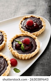 Tarta de chocolate con frambuesas frescas en plato festoneado blanco