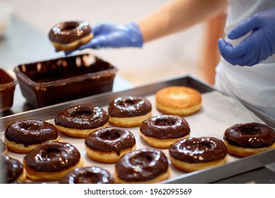 Chocolate topping on donuts in a working atmosphere in a candy workshop. Pastry, dessert, sweet, making