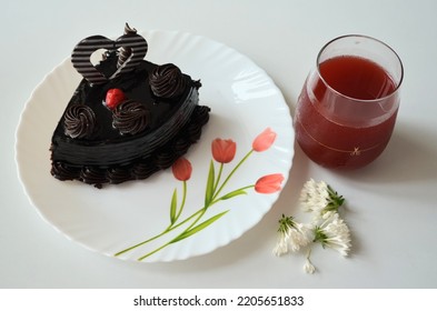 Chocolate Truffle Cake Piece A Chocolate Layer With Dense, Moise Silky Chocolate Cake.Sweet,dark In Colour.Simple Textured Dollops Of Frosting And Chocolate Heart On Top Red Cherry On It.soft Drink.