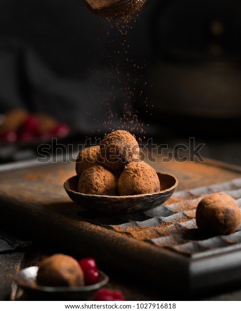 Chocolate truffle. Dark\
chocolate and cherry candy sprinkled with cocoa on a dark wooden\
background in rustic style. Atmospheric food photo. \
Homemade\
fresh energy balls.