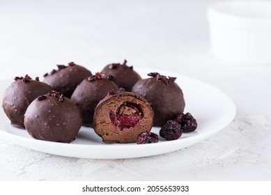 Chocolate truffles with cherry filling in cognac on a white plate. Sugar, gluten and lactose free and vegan.
