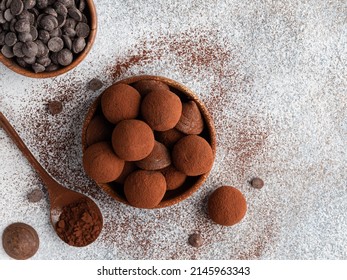 Chocolate truffles covered with cocoa powder in brown wooden bowl with dark chocolate pieces and cocoa powder in wooden spoon. Gray background. Top view table. Delicious candies, tasty dessert. - Powered by Shutterstock