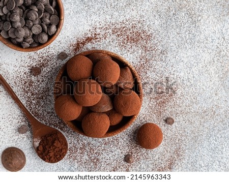 Chocolate truffles covered with cocoa powder in brown wooden bowl with dark chocolate pieces and cocoa powder in wooden spoon. Gray background. Top view table. Delicious candies, tasty dessert. Foto d'archivio © 