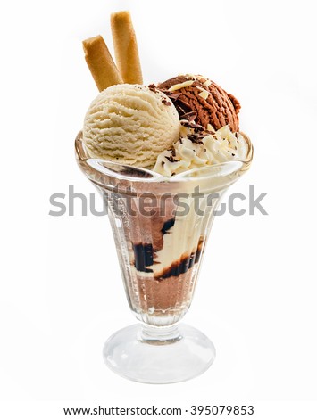 Chocolate and vanilla ice cream sundae in a tall glass topped with nut pieces and decorated with rolled wafers