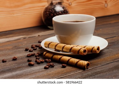 chocolate wafer rolls on a saucer, coffee, teapot.