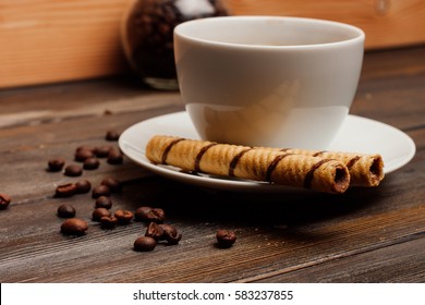 chocolate wafer rolls on a saucer, coffee, teapot