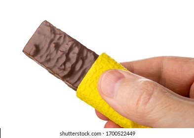 Chocolate Wafer Wrapped In Yellow Paper Napkin In Male Hand Isolated On White Background