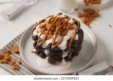 chocolate waffle pancakes, with different creations, drizzled with milk cream sauce, caramel glaze and sprinkled with biscuit crumbs, on a white ceramic plate, rustic white background, selected focus, - Powered by Shutterstock