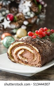 Chocolate yule log cake with red currant on wooden background

