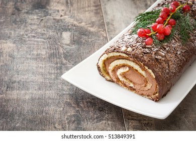 Chocolate yule log christmas cake with red currant on wooden background.Copyspace
 - Shutterstock ID 513849391