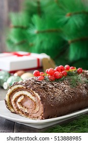 Chocolate yule log christmas cake with red currant on wooden background
