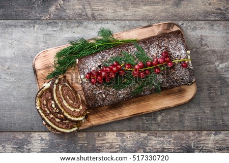 Chocolate yule log christmas cake with red currant on wooden background.copyspace
