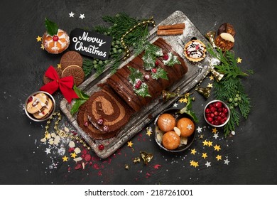 Chocolate yule log on dark background. Traditional dessert of Christmas time. Top view, copy space