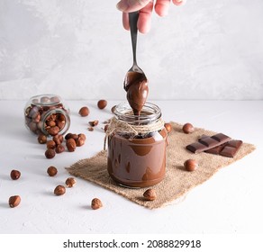 Chocolate-nut paste in a glass jar on a light table. With a spoon, the paste pours into the jar - Powered by Shutterstock