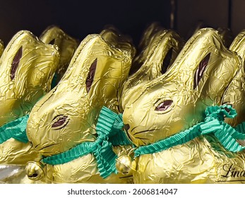 Chocolates in the shape of a cute Easter bunny wrapped in gilded paper are on the market shelf.