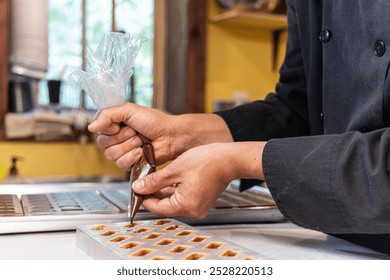 Chocolatier carefully squeezing melted chocolate from a piping bag into a mold, crafting delicious handmade chocolates. Selective focus - Powered by Shutterstock