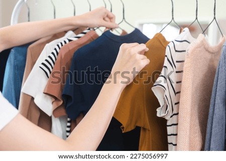 Choice of clothes, Nothing to wear asian young woman, girl hand in choosing dress, outfit on hanger in wardrobe in room closet at home. Deciding what to put on which one.