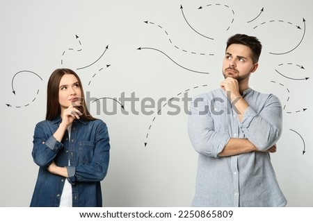 Choice in profession or other areas of life, concept. Making decision, thoughtful young man and woman surrounded by drawn arrows on light background