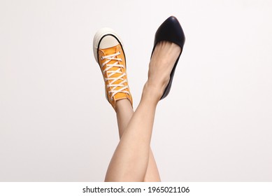 Choice of shoes. Female bare feet in sneaker and high heel shoe on white background. Fashion concept 