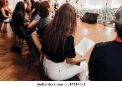 Choir rehearsal, vocal class singing in the auditorium hall, group of students on stage holding white sheets and singing, orchestra vocals class in music school with a teacher, adults sing in chorus - Powered by Shutterstock