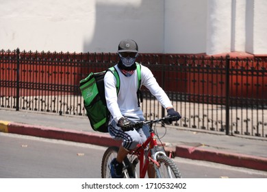 Cholula, Puebla, Mexico; 04-21-2020: Uber Eats Delivery Guy Riding A Bicycle And Wearing A Face Mask For Protection Of Corona Virus