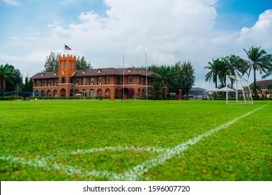 Chonburi, Thailand - 06/12/2019: outdoor green soccer field and international school building with palm trees on background