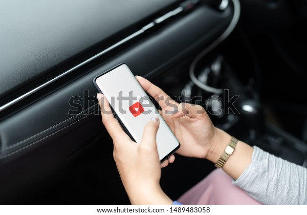 Chonburi, Thailand - Aug 25, 2019: Women\
watching Youtube streaming app on mobile smartphone screen media,\
Creator is international library of lifestyle TV and movies online\
in car transportation