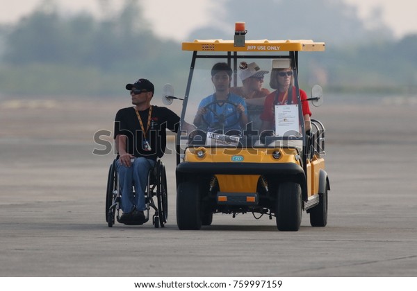 CHONBURI - THAILAND Nov, 17 : Staff coach on the\
wheel chair and drive yellow golf car in The Air Race 1 Thailand\
champion ship on November 17, 2017 at U-Tapao International\
Airport, Chonburi,\
Thailan
