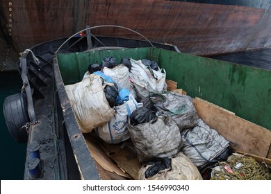 Chonburi, Thailand - OCTOBER 22, 2019: a garbage collection boat from authority collecting trash from barges and commercial ships on the sea.
