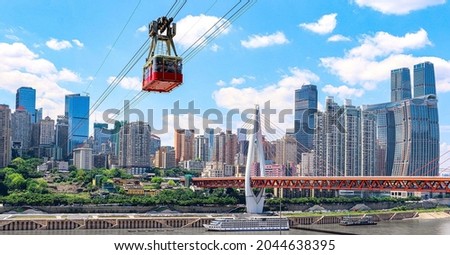 A Chongqing cable car crosses the Yangtze River from Yuzhong District, passing the Dongshuimen bridge - words on cable car translates as 'Chongqing: a tour in Chongqing, a gain in vision'