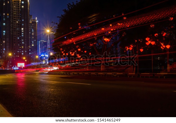Chongqing, China - March 19, 2018: Long\
exposure night cityscape. Road, light trails from cars, buildings\
on the background in the Chinese city of Chongqing.\
