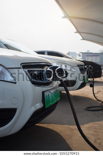 Chongqing, China — March 24, 2018: New energy\
vehicles, electric vehicles are charging at charging stations, in\
the setting sun
