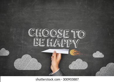 Choose To Be Happy Concept On Black Blackboard With Businessman Hand Holding Paper Plane