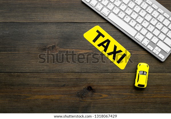 Choose, select taxi concept. Order taxi online. Sign\
ner car toy and keyboard on dark wooden background top view space\
for text