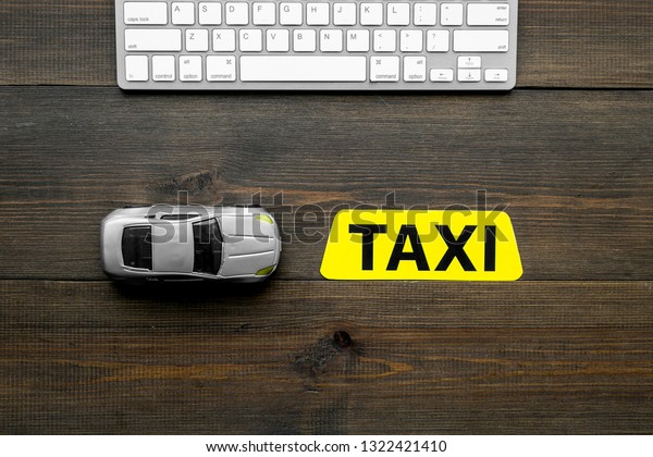 Choose, select taxi concept. Order taxi online. Sign\
ner car toy and keyboard on dark wooden background top view space\
for text