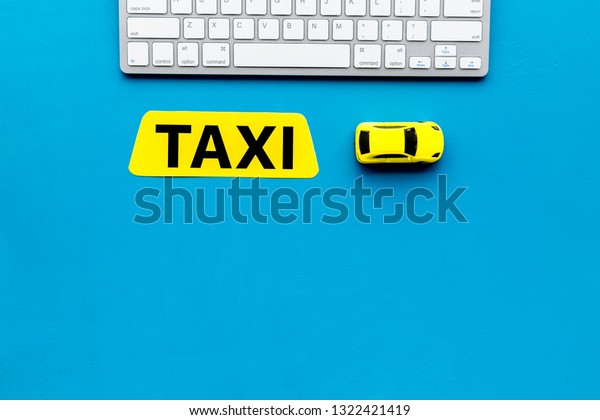 Choose,
select taxi concept. Order taxi online. Sign ner car toy and
keyboard on blue background top view copy
space