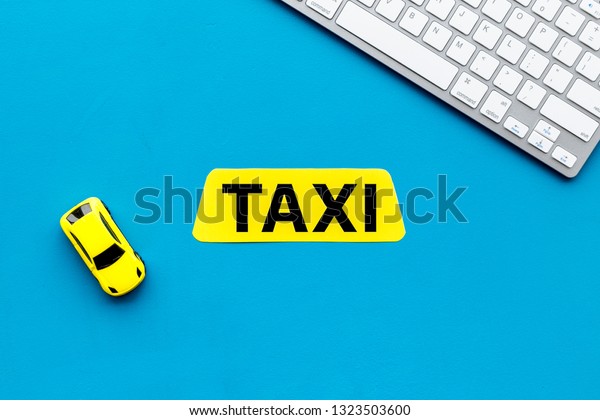 Choose,\
select taxi concept. Order taxi online. Sign ner car toy and\
keyboard on blue background top view copy\
space