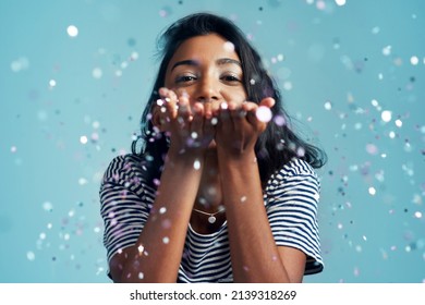 Choose what makes you happy. Cropped shot of a beautiful young woman blowing confetti in the studio.