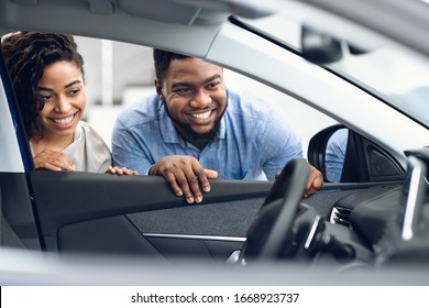 Choosing Auto. Black Couple Looking At Car Interior Buying Family Automobile In Dealership Showroom. Selective Focus, Free Space