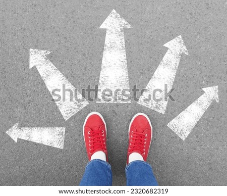 Choosing future profession. Girl standing in front of drawn signs on asphalt, top view. Arrows pointing in different directions symbolizing diversity of opportunities