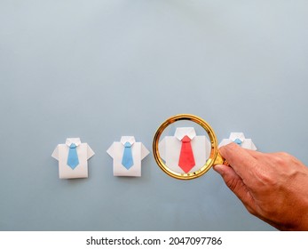 Choosing good employee leader. Man consider and look for employee leader by magnifying glass in the hand an employee in shirt and red tie. Staff recruitment.