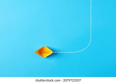 Choosing The New, Right Or Alternative Change Path In Business Concept. Yellow Paper Boat Makes A Turn And Changes Direction On Blue Background. 