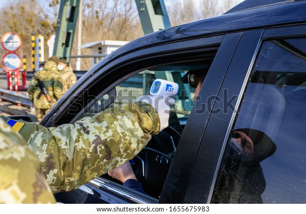 Chop, Ukraine -\
February 25, 2020: Border guard conduct temperature control of\
citizens crossing the border at Ukrainian checkpoints. Coronavirus\
protection in Ukraine.
