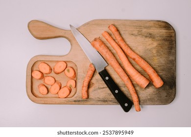 Chopped carrots on a wooden cutting board surrounded by a variety of fresh vegetables, symbolizing World Vegan Day and promoting healthy, plant-based eating - Powered by Shutterstock