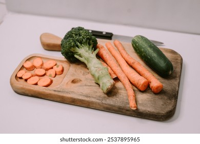 Chopped carrots on a wooden cutting board surrounded by a variety of fresh vegetables, symbolizing World Vegan Day and promoting healthy, plant-based eating - Powered by Shutterstock