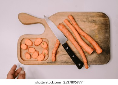 Chopped carrots on a wooden cutting board surrounded by a variety of fresh vegetables, symbolizing World Vegan Day and promoting healthy, plant-based eating - Powered by Shutterstock