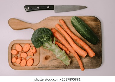 Chopped carrots on a wooden cutting board surrounded by a variety of fresh vegetables, symbolizing World Vegan Day and promoting healthy, plant-based eating - Powered by Shutterstock