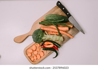 Chopped carrots on a wooden cutting board surrounded by a variety of fresh vegetables, symbolizing World Vegan Day and promoting healthy, plant-based eating - Powered by Shutterstock